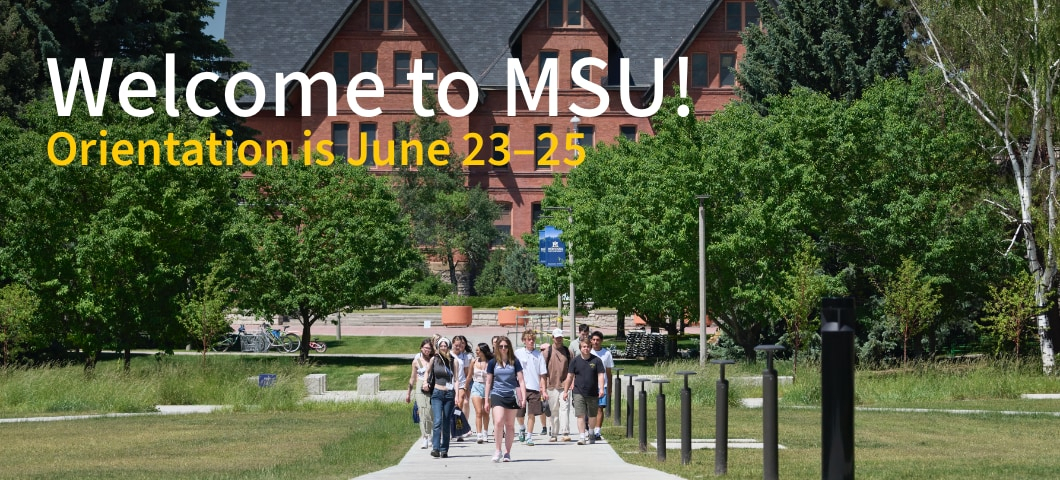 A group of students and families walk along a campus pathway surrounded by green trees at Montana State University on a sunny day. In the background is a large brick building with peaked roofs. Overlaid text reads: “Welcome to MSU! Orientation is June 23– | MSU