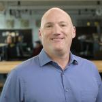 Brock LaMeres smiles at the camera wearing a collared shirt