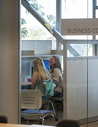 two people sit at a desk behind a glass wall