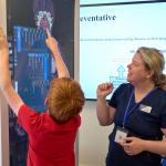 A teacher and a student interacting with a 7-foot-tall digital display showing human anatomy
