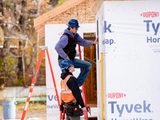 Men lean on a ladder and look at the frame of a building | 