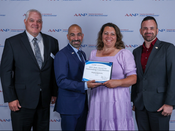 A woman holding an award certificate stands among three men in suits.  | Submitted photo