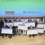 Students stand with oversized checks representing their winnings from an entrepreneurial competition.