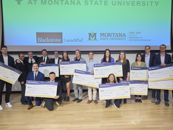 Students stand with oversized checks representing their winnings from an entrepreneurial competition. | 