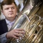 A man holds a concert tuba while looking to the left of the frame