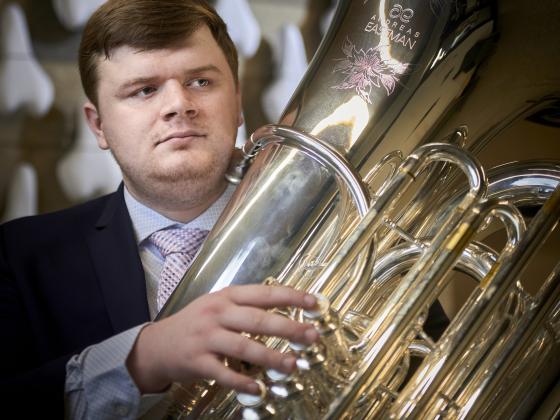 A man holds a concert tuba while looking to the left of the frame | MSU photo by Colter Peterson