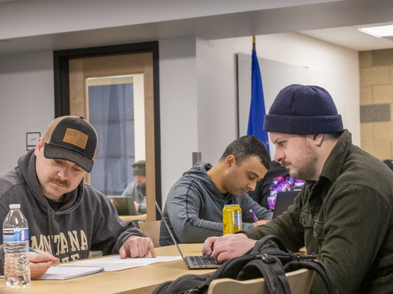 four people sit at desk and collaborate on homework | MSU photo bt Doc Cravens