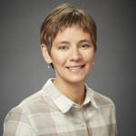 A woman in a checkered shirt in front of a gray background