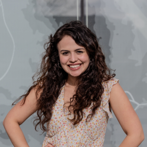 A young woman poses for a portrait in front of a gray wall.