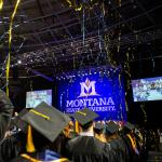 streamers fly over graduates in caps and gowns at graduation