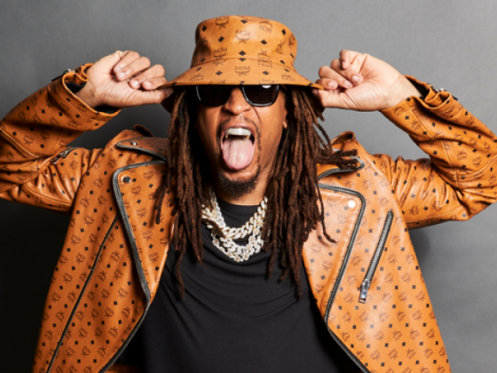 Photo of a man wearing sunglasses and an orange hat and jacket, with his mouth open. | 