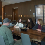Four people sitting around a table in a hotel lobby