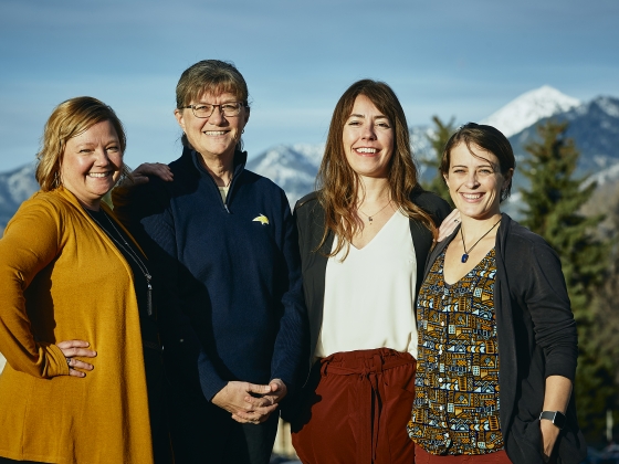 Four women pose for a portrait in the afternoon sunlight with a snowy peak in the background. | MSU Photo by Adrian Sanchez-Gonzalez