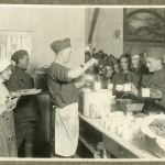 Vintage photo of two World War I soldiers feed fellow soldiers who line up for food.