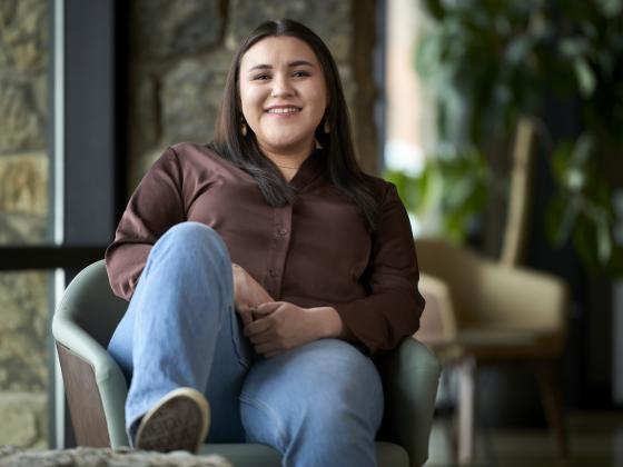 Tillie Stewart sits back in a chair with her foot up on a rock and a stone wall in the background alongside a leafy plant | MSU photo by Colter Peterson