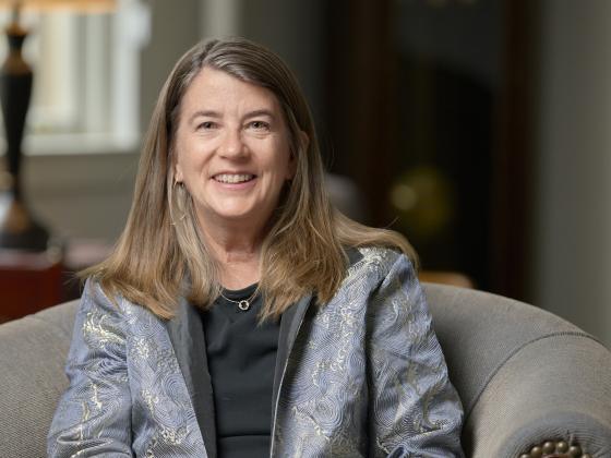 Liz Shanahan sits on an armchair looking at the camera in front of an out of focus background | MSU photo by Colter Peterson