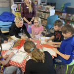 A group of children with teachers working around a table in a classroom.
