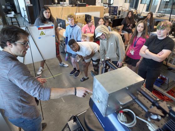 A group of high school students crowd around a large device in a lab | MSU photo by Colter Peterson
