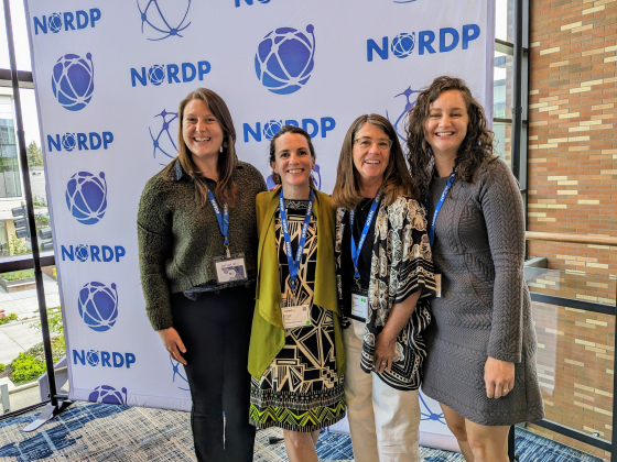 a group of women smiling in front of a white and blue backdrop | Image courtesy of Nicole Motzer