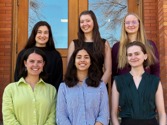 A group of students pose in front of a brick building