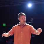 A man moves his hands to conduct a choir.