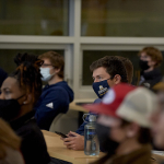 A group of students sit in a classroom watching a speaker.