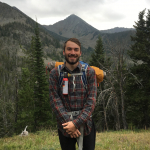 A man in a backpack in front of a mountain scene