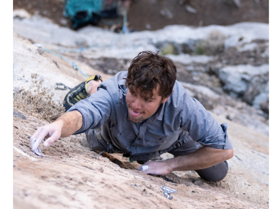 A young man climbs a rock wall | Image Courtesy of Justin Case