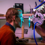 Tristan Sampley looking into a technical piece of laboratory equipment