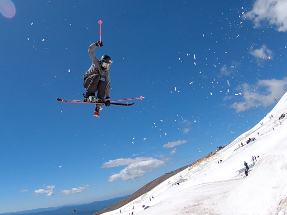 A skier flying through the air with a blue sky in the background. | photo courtesy Maggie Voisin