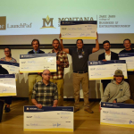 Entrepreneurs pose with extra large checks after a venture competition.