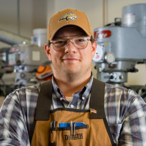 Darin Mydland standing in front of machining equipment wearing safety equipment.