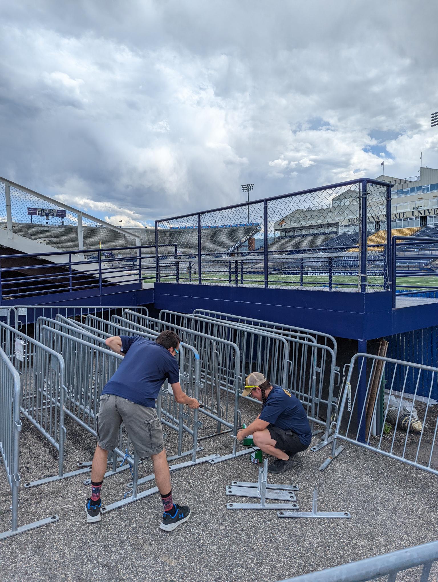 Student employees helping put fences up at football game