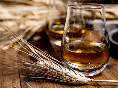 barley in front of a glass of whiskey