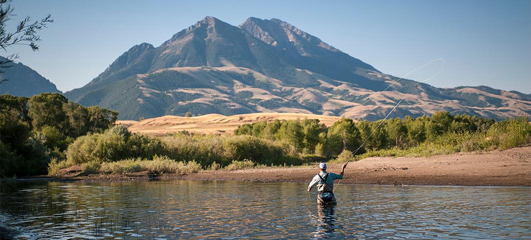 Scenic shot of fisherman in a body of water with a mountain in the distance