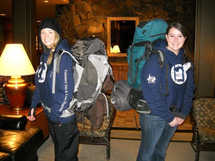 Two students wearing blue sweatshirts and large backpacks