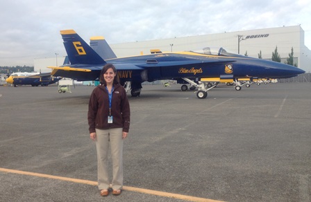 A student stands in front of a blue and gold jet