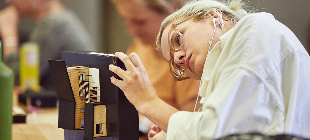 A woman working on a scale model of a tiny house.