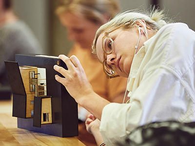 Student examining a scale model of a tiny home.