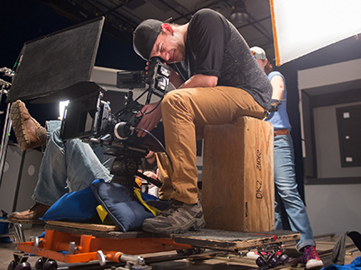 Student looking through the viewfinder of a motion film camera upon a dolly