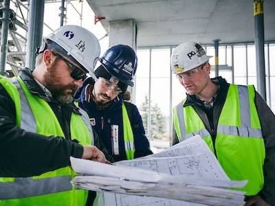 two students look at construction drawings with worker