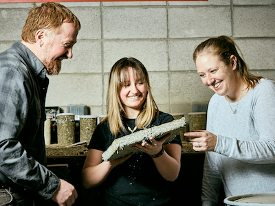 Photo of three people holding sample of hempcrete material and smiling. placeholder image