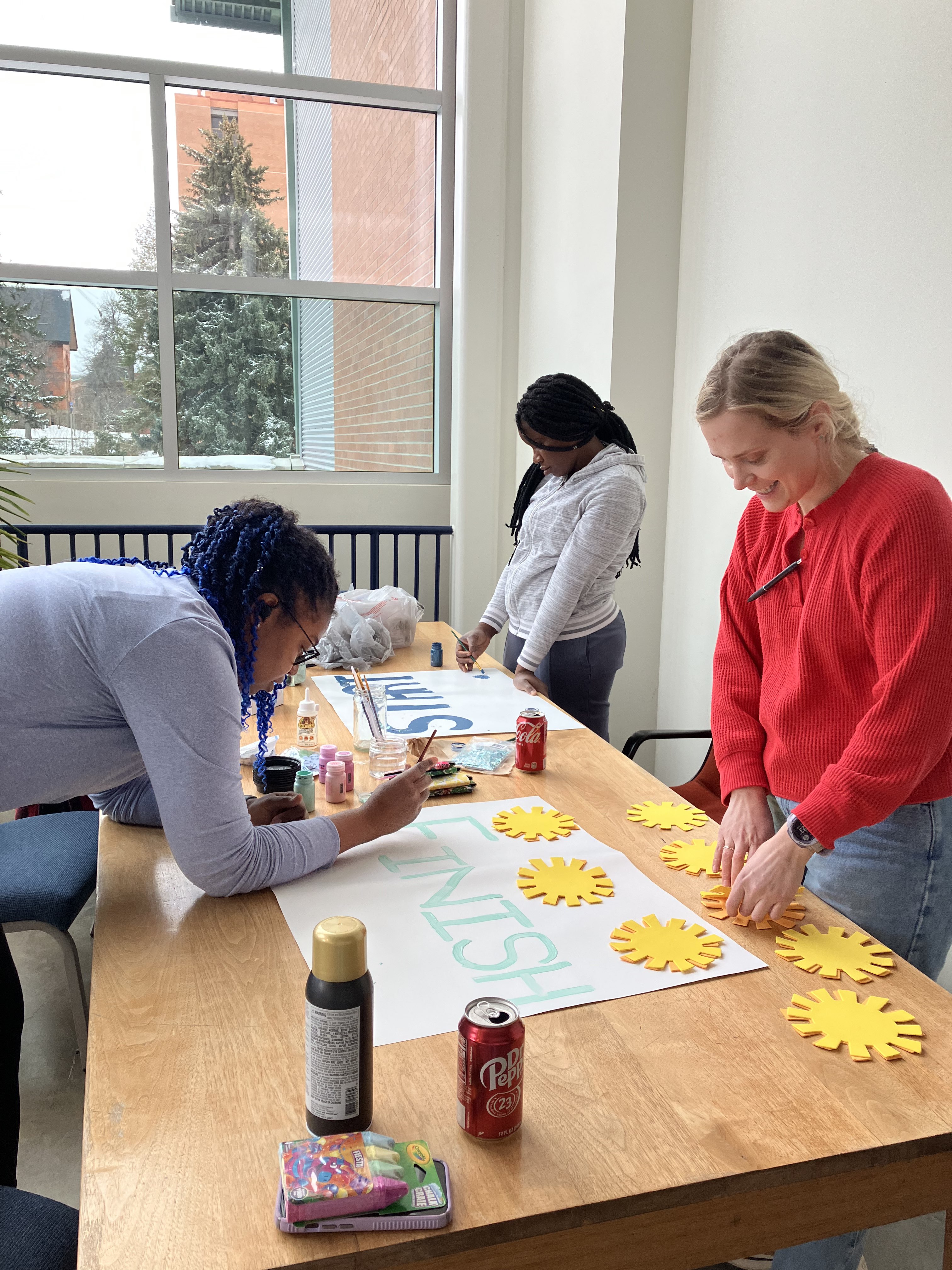 3 grad students decorating fun run posters in 2023