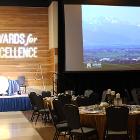 Image of round table, projector screen and lit stage.