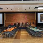 Centered image of long tables with screes and stage in the background.