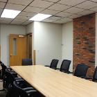 Room 234 has a conference table and 12 office chairs. White board is in the room. View is from the side.