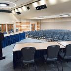 Theater style seating. Lights are all the way on. Ballroom A air-wall is up. A lectern and panel tables with skirting are on the former stage. View is from former stage.