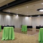 Image of standing tables with lime green tablecloths with white curtains in the background.