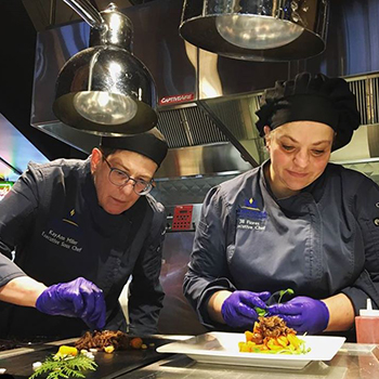 two female chefs plating food 