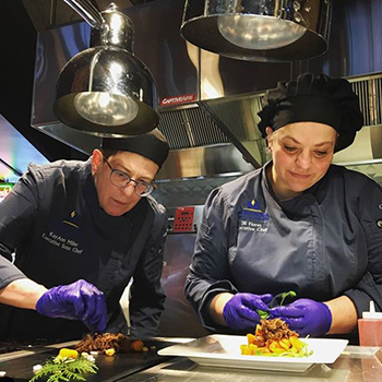 two female chefs plating food